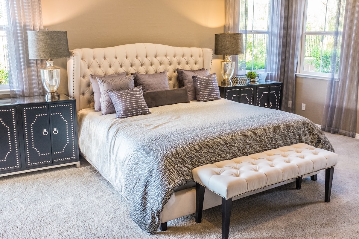 A plain bedroom with blackout blinds part-drawn and a simple firm bed.