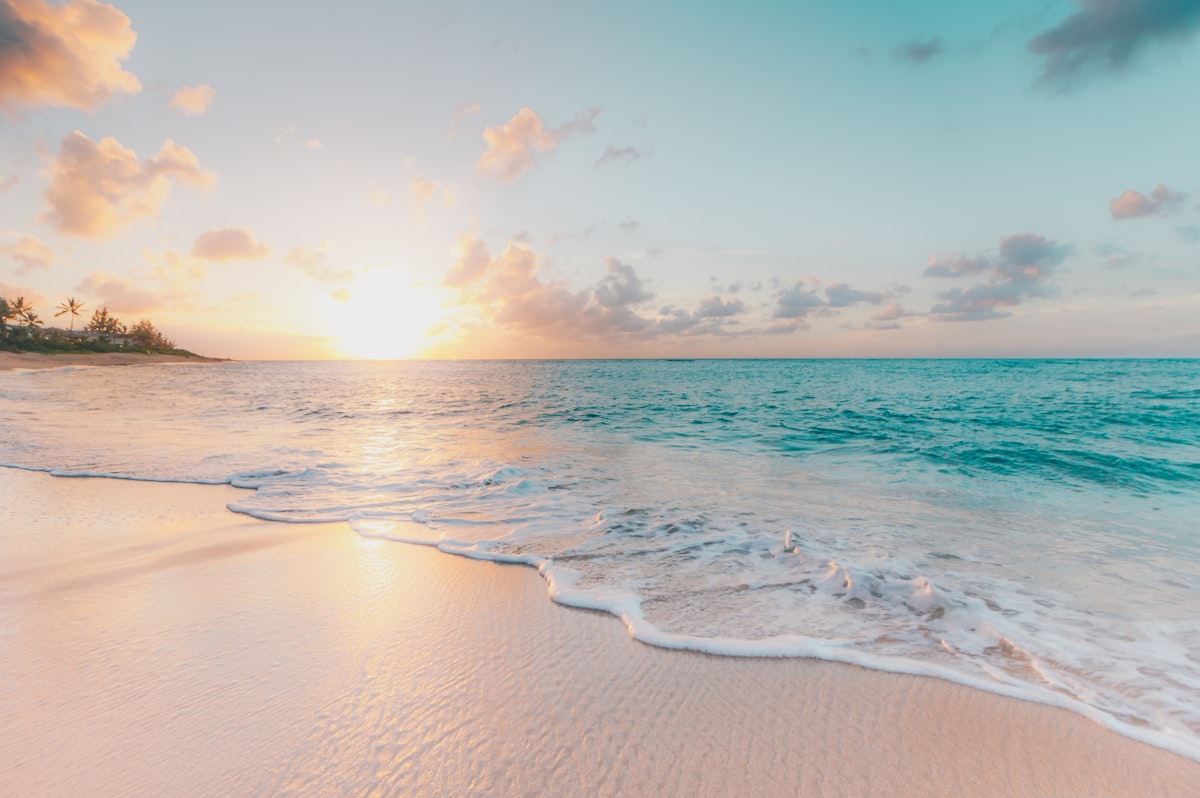 A wide sandy beach with a firm accessible boardwalk leading onto the sand.