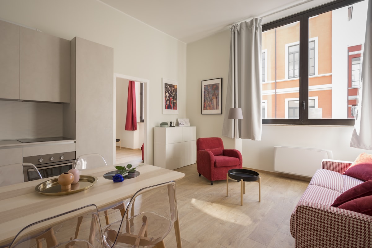 An open living room with a low sofa, wood floor and a large window facing the harbour.